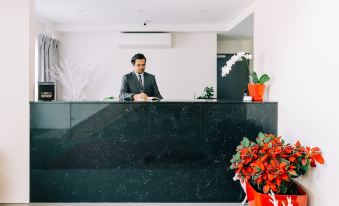 a man is standing behind a black counter in a room with red flowers and a reindeer figurine at Voyager Motel