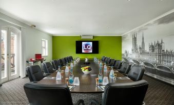 a conference room with a large table and chairs , a television on the wall , and water bottles at Lion Quays Resort