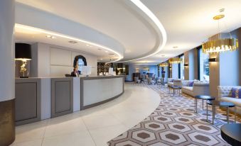 a modern hotel lobby with a curved reception desk , a couch , and a potted plant at Hotel Bahia