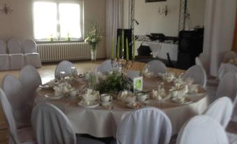 a large , round table with white linens and a centerpiece is set for a formal dinner at Weißes Haus