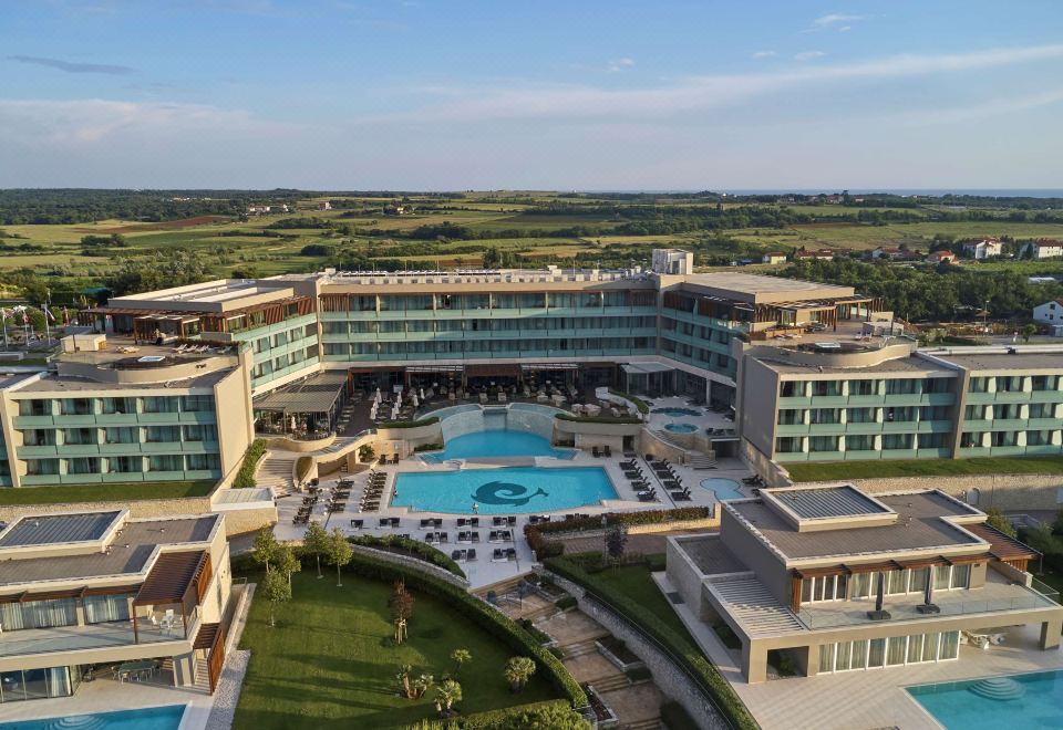 aerial view of a large hotel with a pool surrounded by grass and trees , situated near a body of water at Kempinski Hotel Adriatic Istria Croatia