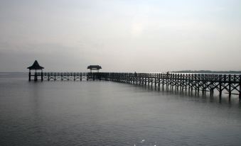 a wooden pier extending into a body of water , with a building on the other side at Bromo Park Hotel Probolinggo