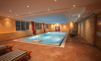 a large indoor swimming pool with multiple lanes , surrounded by lounge chairs and buildings , under the glow of lights from the sun at Bellevue Rheinhotel