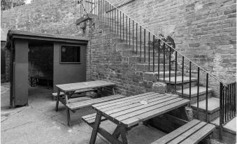 a black and white photo of a brick building with outdoor benches and tables in the yard at The Punch Bowl