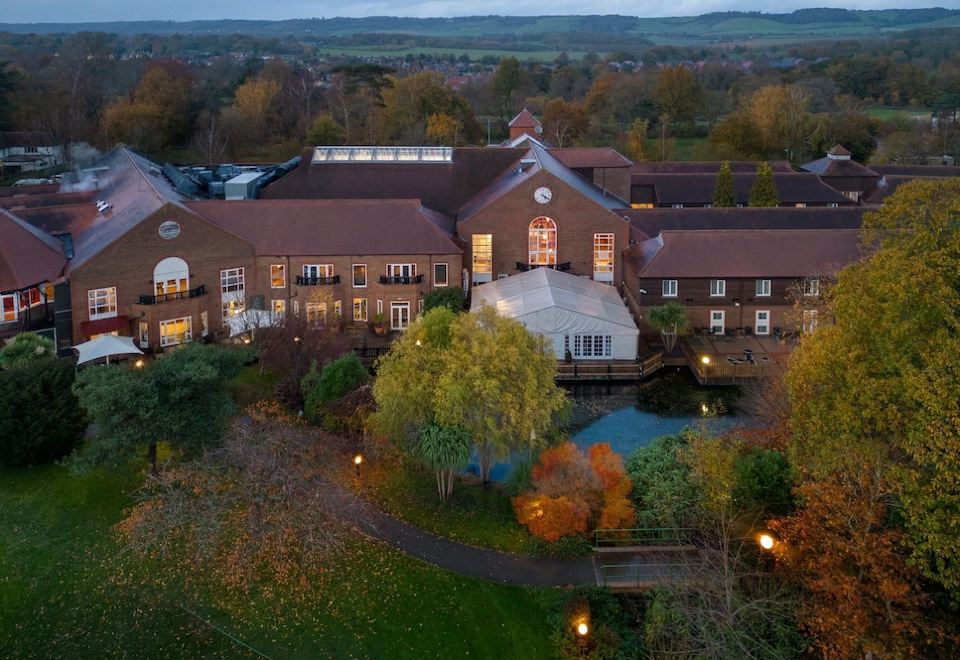 aerial view of a large , brown building with a pond in front of it , surrounded by trees and grass at Delta Hotels Tudor Park Country Club