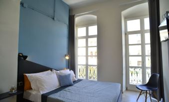 a modern bedroom with a blue and white color scheme , large windows , and a bed at Habit