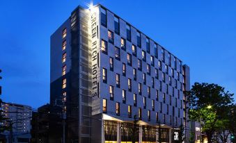 "a modern hotel building with a large glass facade and the name "" ruth "" displayed prominently" at Green Rich Hotel Kurume