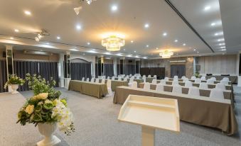 a large conference room with multiple rows of chairs arranged in a semicircle , and a podium at the front of the room at Chaipat Hotel