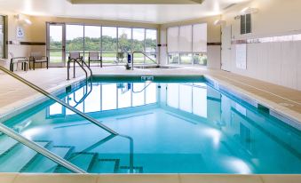 an indoor swimming pool with blue water , surrounded by windows that provide natural light and views of the outdoors at Courtyard Omaha Bellevue at Beardmore Event Center