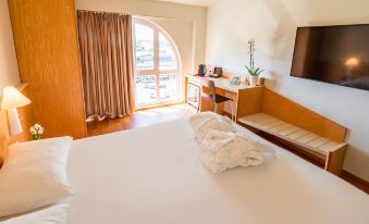 a large bed with white sheets is in a room with a wooden headboard , a window , and a desk at Ibis Firenze Nord Aeroporto