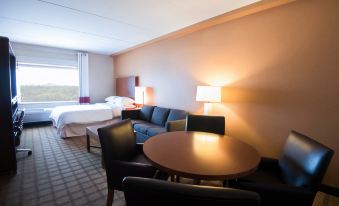 a hotel room with a bed , couch , table , and lamps , giving it a cozy and comfortable appearance at Four Points by Sheraton Winnipeg South