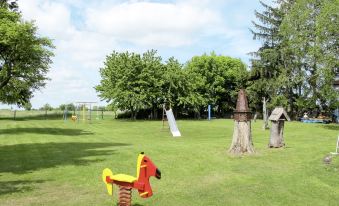 a large , well - maintained grassy field with a variety of playground equipment , such as swings , slides , and a jungle gym at Mary