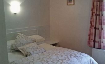 The bedroom has two beds and an open doorway leading to another room at The Grant Arms Hotel