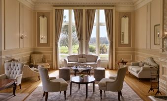 a spacious living room with large windows , beige walls , and beige sofas , along with coffee tables and cushions at Rockliffe Hall Hotel Golf & Spa