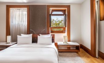 a large bed with white linens and a wooden headboard is situated in front of a window at Aman Sveti Stefan