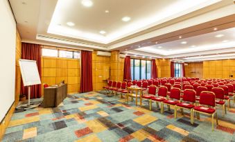 a large conference room with wooden walls and a carpeted floor , filled with red chairs arranged in rows at Riviera Hotel