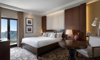 a large , well - made bed with white linens is in a hotel room next to a table and lamp at Renaissance Tuscany Il Ciocco Resort & Spa