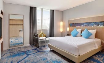 a modern hotel room with a large bed , blue and white carpet , and a window at Novotel Jakarta Mangga Dua Square
