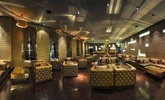a luxurious living room with gold and black furniture , including couches , chairs , and a dining table at Radisson Hotel New Delhi Paschim Vihar