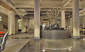 a grand hotel lobby with marble floors , a reception desk , and several chandeliers hanging from the ceiling at Grand Hotel Et des Palmes