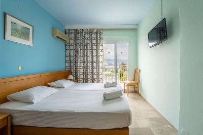 a hotel room with a bed , a tv , and a sliding glass door leading to a balcony at Hotel Summery