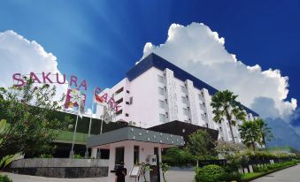 "a large white building with the words "" cora hotel "" prominently displayed on its facade , surrounded by greenery and blue skies" at Sakura Park Hotel & Residence