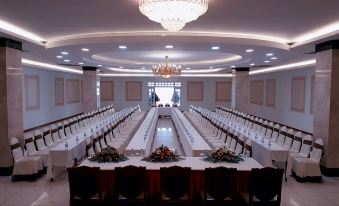 a large banquet hall with long tables and chairs , a chandelier , and a crystal chandelier at Tre Xanh Hotel