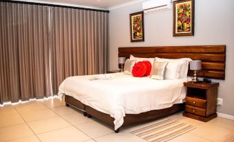 a large bed with white sheets and a red pillow is in a room with a brown headboard at Balmoral Lodge