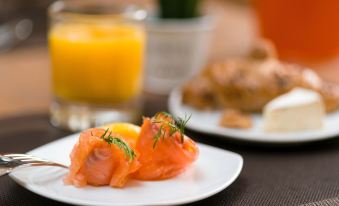 a plate with two pieces of smoked salmon on a stick , accompanied by a cup of orange juice at Hotel Moments Budapest
