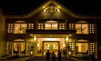 a group of people standing in front of a large , two - story house with a well - lit interior at Hotel Venezia