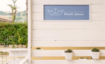 "a blue and white sign for the "" nankawu beach house "" is displayed on a white wall" at Beach House