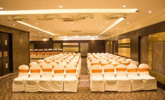 a large conference room with rows of white chairs and orange stools arranged for a meeting or event at Hotel Celebration