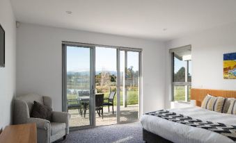 a spacious bedroom with a large bed , a chair , and a sliding glass door leading to a patio at Relbia Lodge