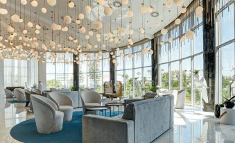 a modern lounge area with white walls , large windows , and a collection of hanging balls at NissiBlu Beach Resort