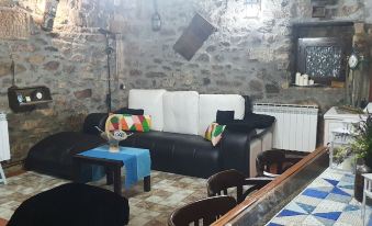 a black and white couch is in a room with a stone wall and tables at Casa Rural la Plazuela de Mari