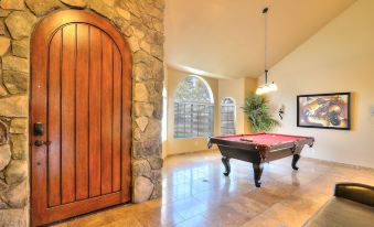 a pool table is set up in a spacious room with stone walls and large windows at Arrowhead