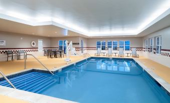 an indoor swimming pool with a large rectangular design , surrounded by chairs and tables for patrons to enjoy at Residence Inn New Bedford Dartmouth