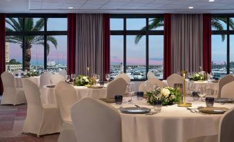 a dining room with white chairs and tables set up for a formal event , with a view of the ocean at Riviera Marriott Hotel la Porte de Monaco