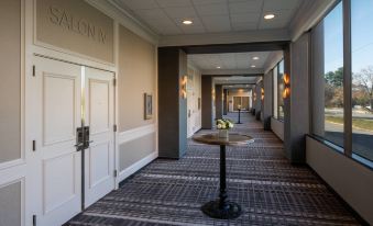 a hotel hallway with a door and a table in the middle , surrounded by white walls at Tysons Corner Marriott