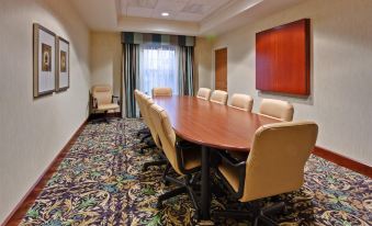 a conference room with a large wooden table , multiple chairs , and a painting on the wall at Staybridge Suites Buffalo
