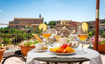 a table with a white tablecloth , wine glasses , plates of food , and cups of orange juice is set on a balcony overlooking buildings at Hotel Minerva