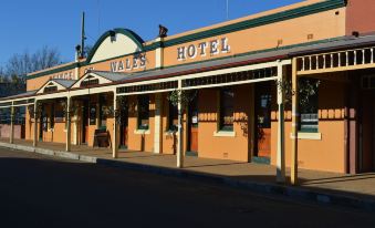 "the entrance of a building named "" wells hotel "" with its name displayed on its sign , under a clear blue sky" at Prince of Wales Hotel Gulgong