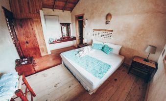 a large bed with a wooden headboard and white sheets is in a room with wooden floors at Altos de Cano Hondo
