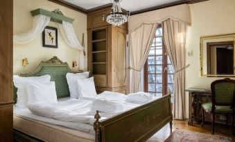 a luxurious bedroom with a large bed , white linens , and a chandelier hanging from the ceiling at Haringe Slott