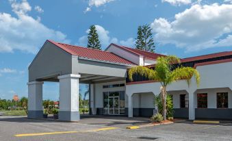 a large white building with a red roof and a palm tree in front of it at Best Western Space Shuttle Inn