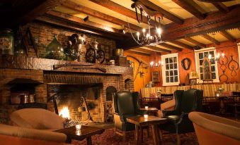 a cozy living room with a fireplace , multiple chairs , and a dining table , creating a warm and inviting atmosphere at Manoir Hovey