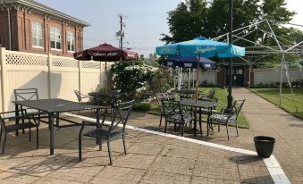 a patio area with several chairs and tables , some of which are covered with umbrellas at Waynebrook Inn