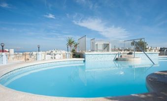 a large outdoor swimming pool surrounded by a patio , with a view of the ocean in the background at Sunflower Hotel