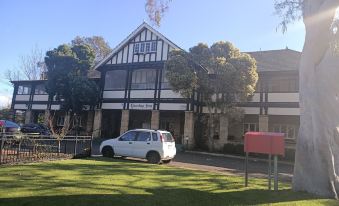 a white car is parked in front of a black and white building with a red mailbox at Yanchep Inn