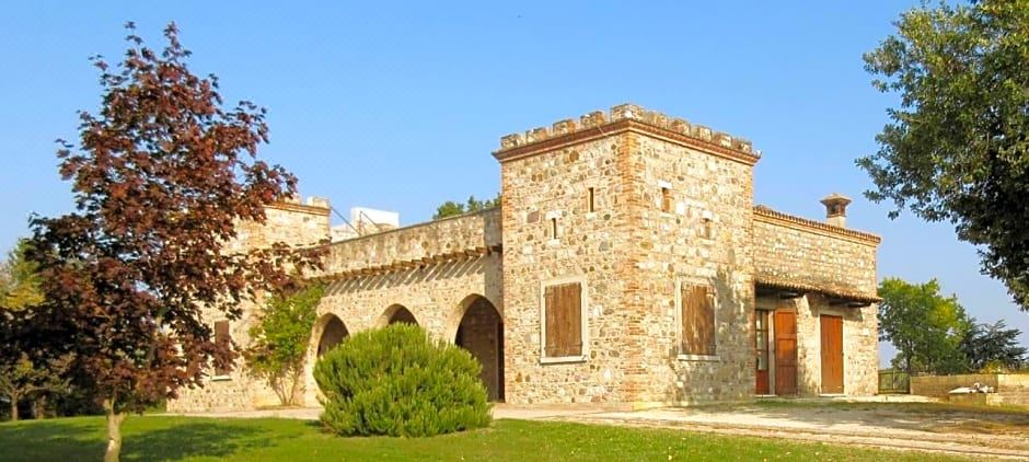 a stone building with arched windows and a red brick tower , situated in a grassy field at Villa Luisa